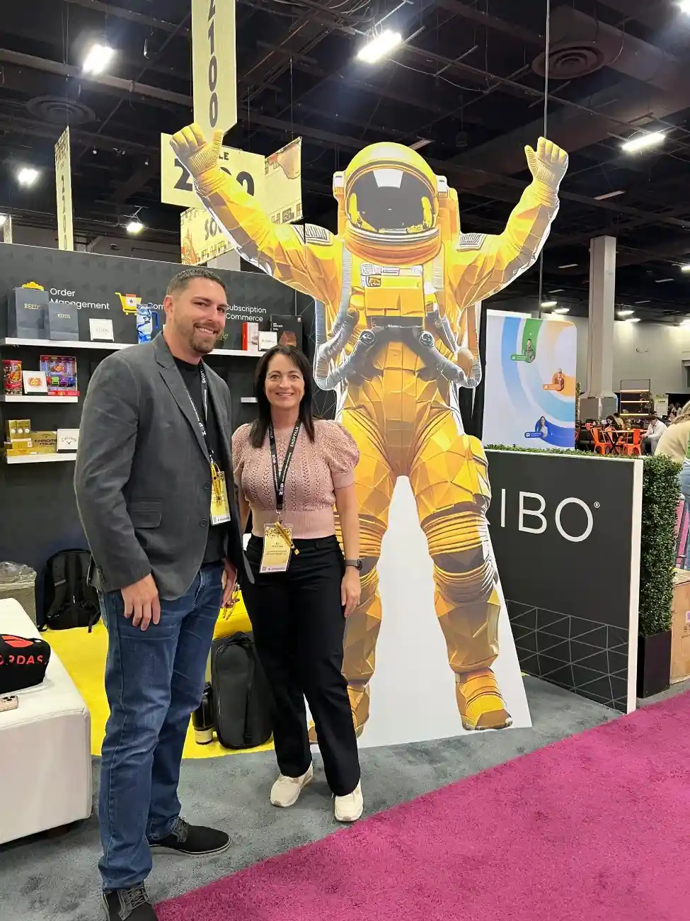 two people standing in front of a cardboard cut out of an astronaut at shoptalk